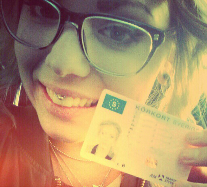 Bild på 18-årig glad tjej med glasögon, hållandes i sitt nytagna körkort. En av många oväntade självständighetskällor.